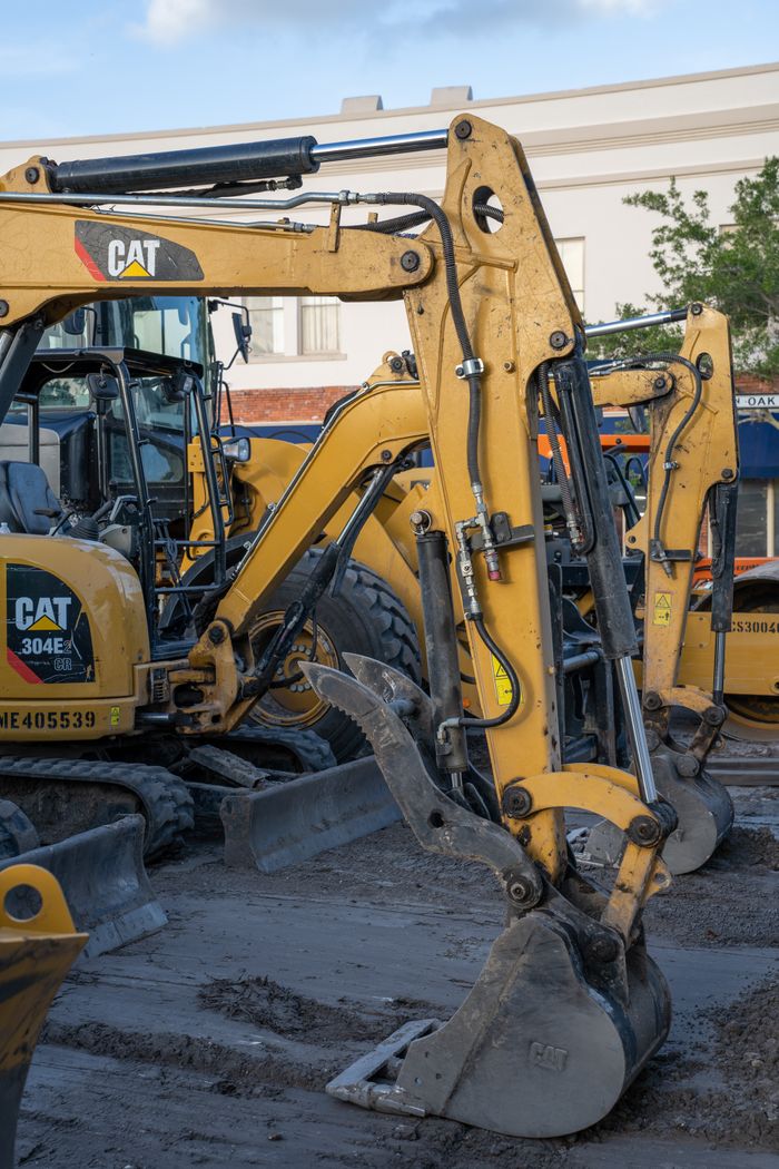 Yellow excavators at a construction site with machinery and equipment in the foreground.